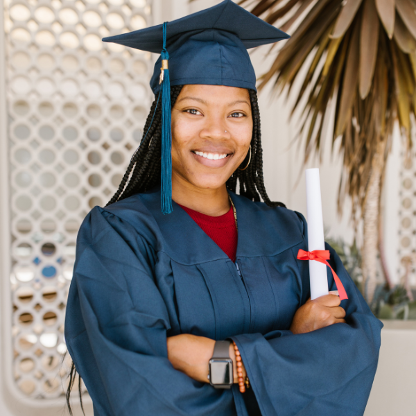 A woman in graduation gear holds a diploma.