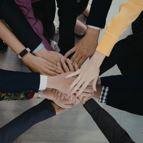 Several women put their hands together in a circle.